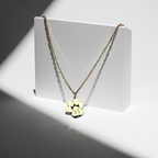 Gold necklace with a paw-shaped pendant on a white stand