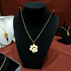 Gold necklace with a paw-shaped pendant on a black stand against a brown background
