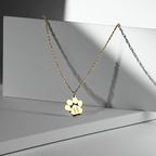 Gold necklace with a paw-shaped pendant on a reflective surface